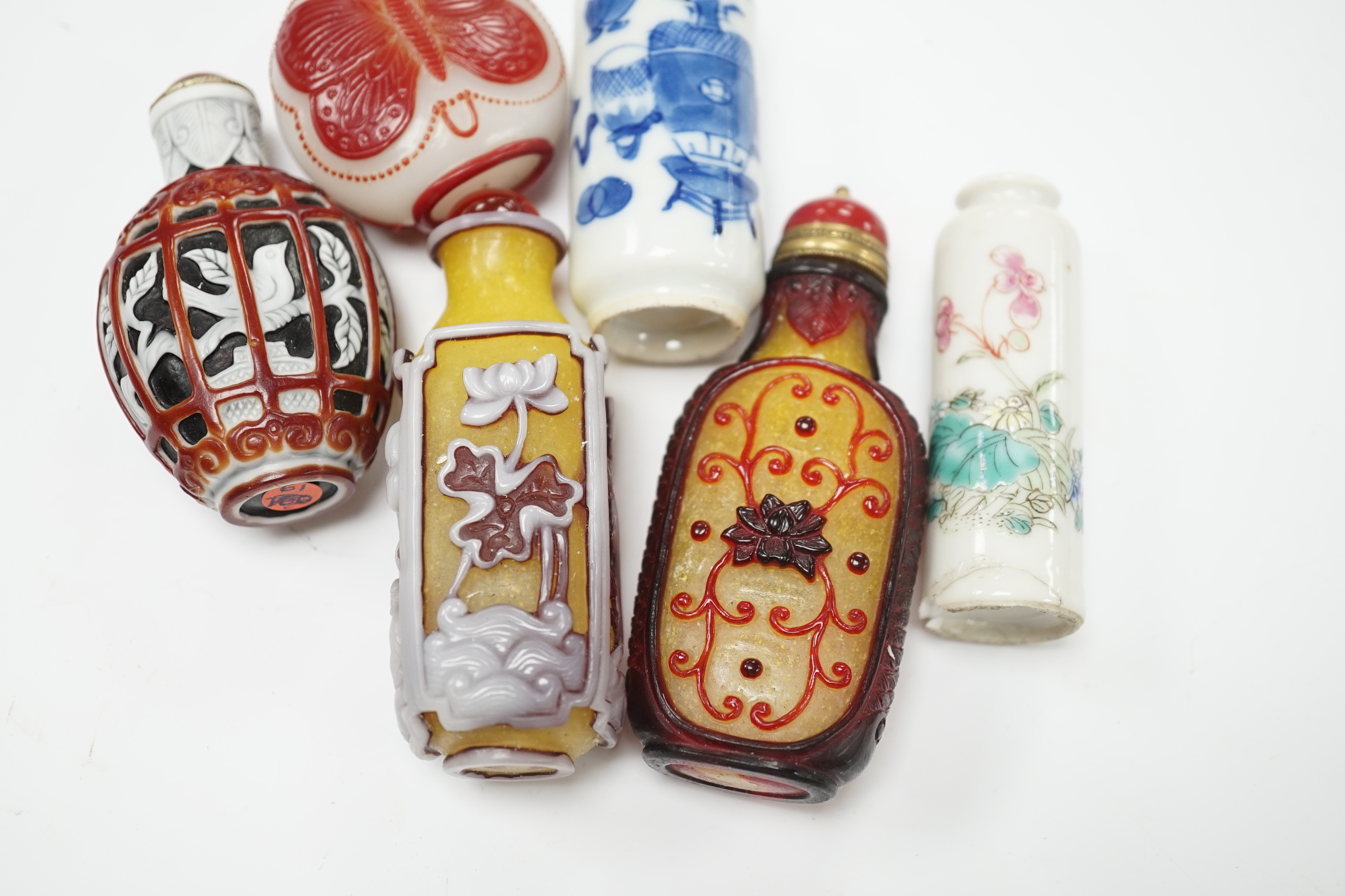 Four Chinese overlaid glass snuff bottles and two Chinese porcelain snuff bottles, three with stoppers, largest 9cm high